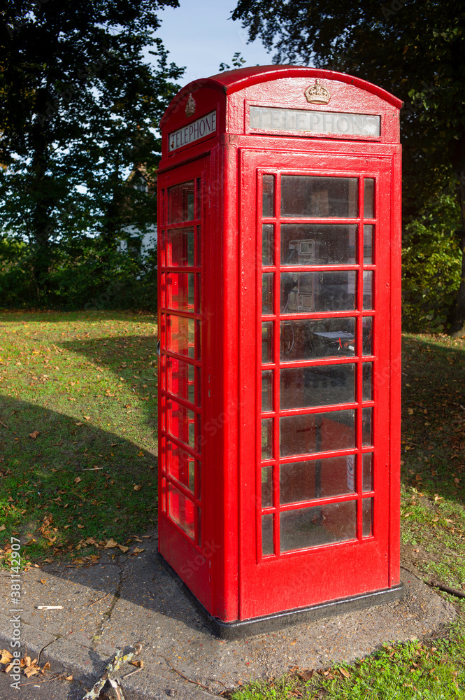 Traditional red telephone box in full sun in a park in the United Kingdom Traditional red telephone box in full sun in a park in the United Kingdom