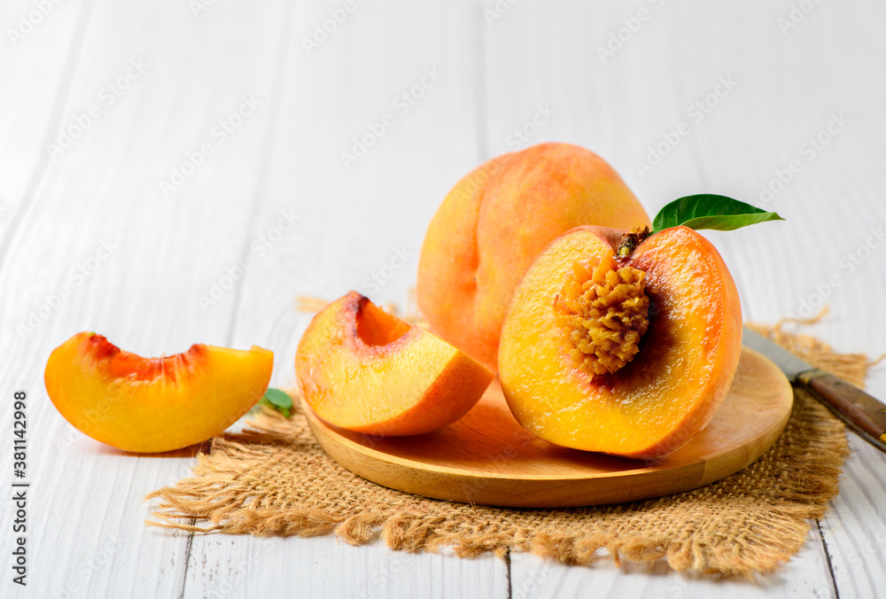 Fresh sweet sliced peach with green leaf on wood plate Fresh sweet sliced peach with green leaf on wood plate