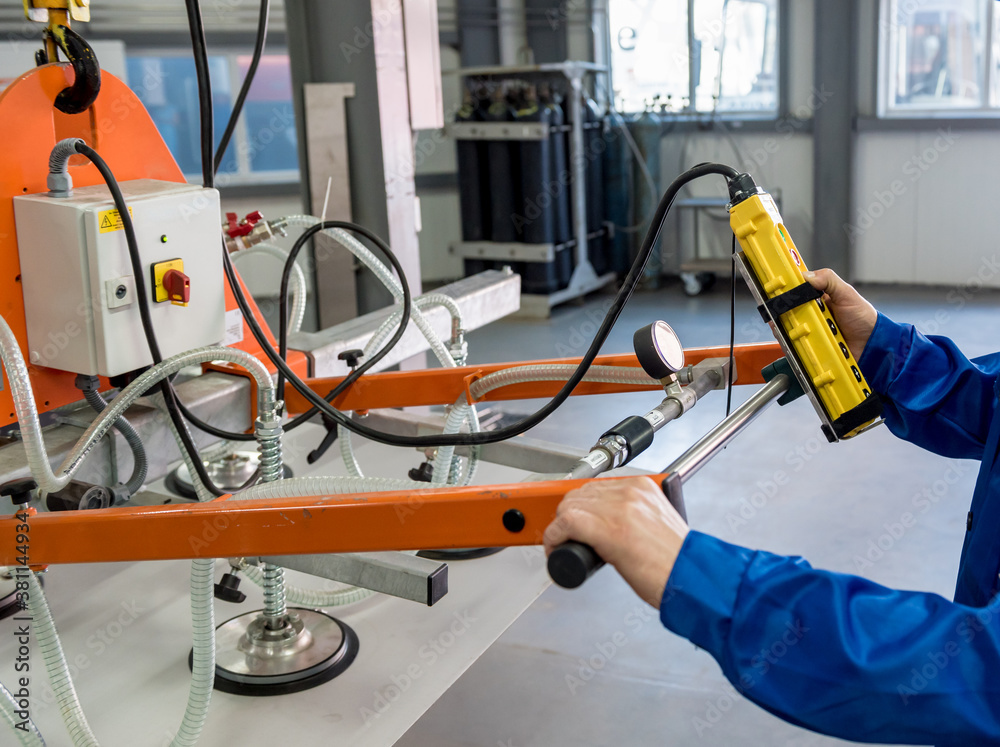 Worker uses suction cups for transporting large sheets of metal Worker uses suction cups for transporting large sheets of metal
