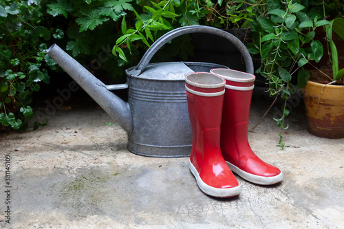 bottes rouges et arrosoir sous la pluie photo
