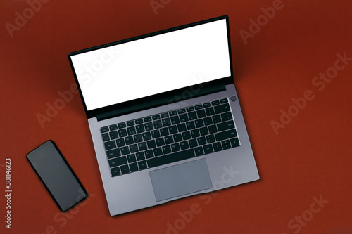 smartphone and a white mockup on a laptop screen on a brown background top view