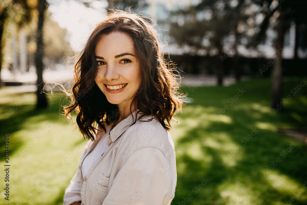 Young cheerful brunette woman outdoors in a park, smiling. Young cheerful brunette woman outdoors in a park, smiling.
