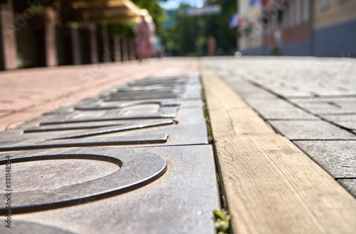 Sidewalk with metal letters and wooden stripe in the city