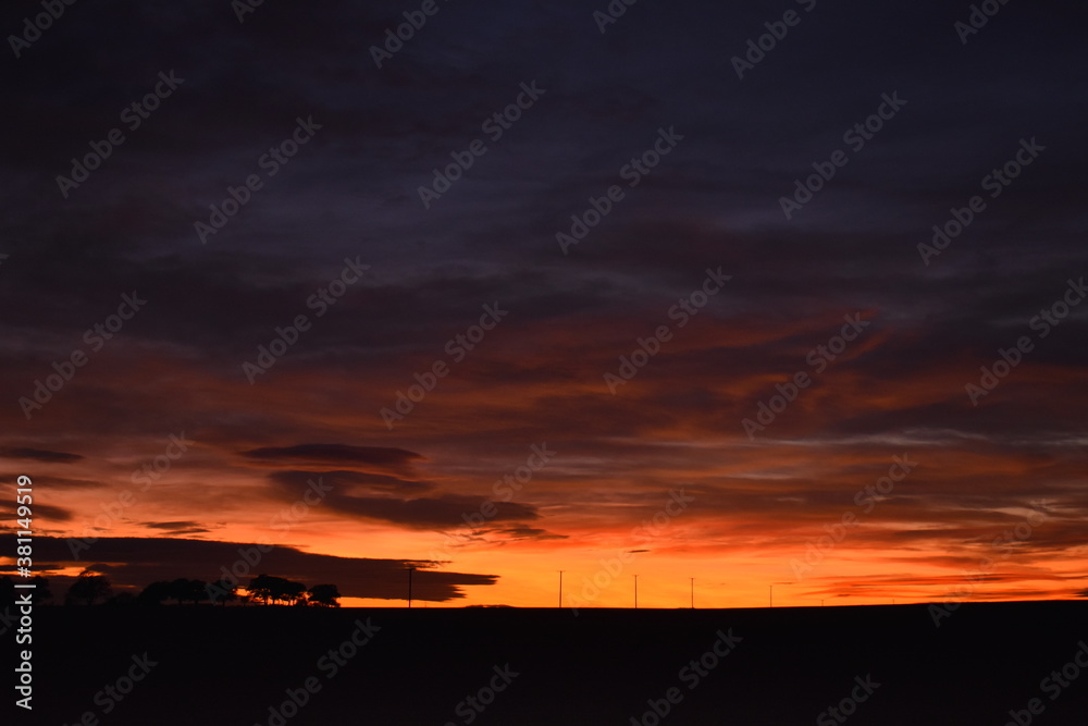 Dramatic inky orange sunset, dark ominous sky with pylons in England