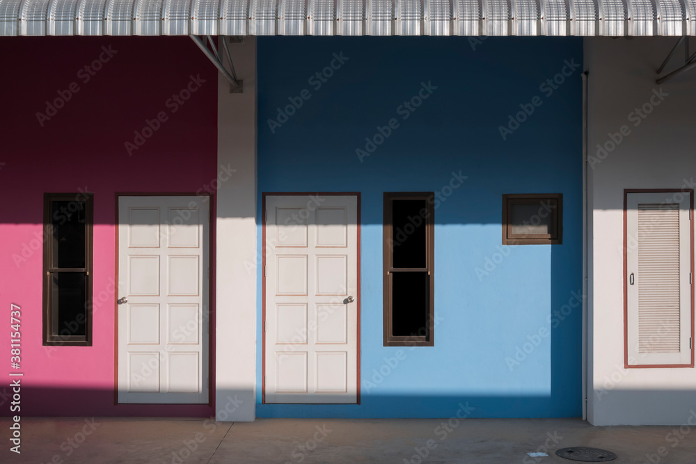 Sunlight and shadow on front doors and storage compartment surface with awning of the blue and pink apartment