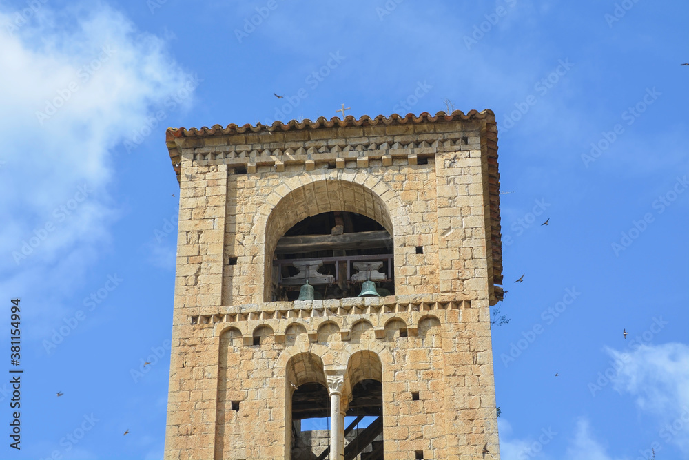 BEGET, CATALONIA, SPAIN, EUROPE, SEPTEMBER 2020. Beautiful tower of the Romanesque church of San Cristóbal surrounded by birds in the beautiful medieval town of Beget.