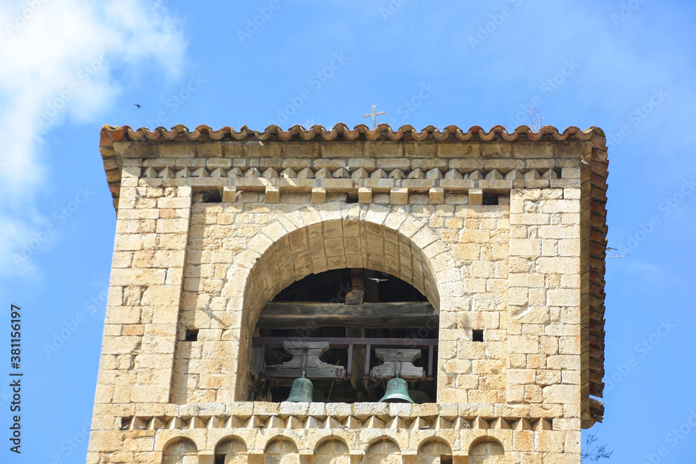 BEGET, CATALONIA, SPAIN, EUROPE, SEPTEMBER 2020. Beautiful tower of the Romanesque church of San Cristóbal surrounded by birds in the beautiful medieval town of Beget.
