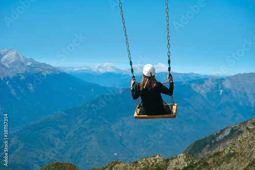unrecognizable woman sitting on swing in mountains, extreme fun and active weekend concept