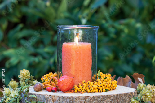 Herbstdekoration mit orange Kerze, Physalis und Feuerdorn-Beeren photo