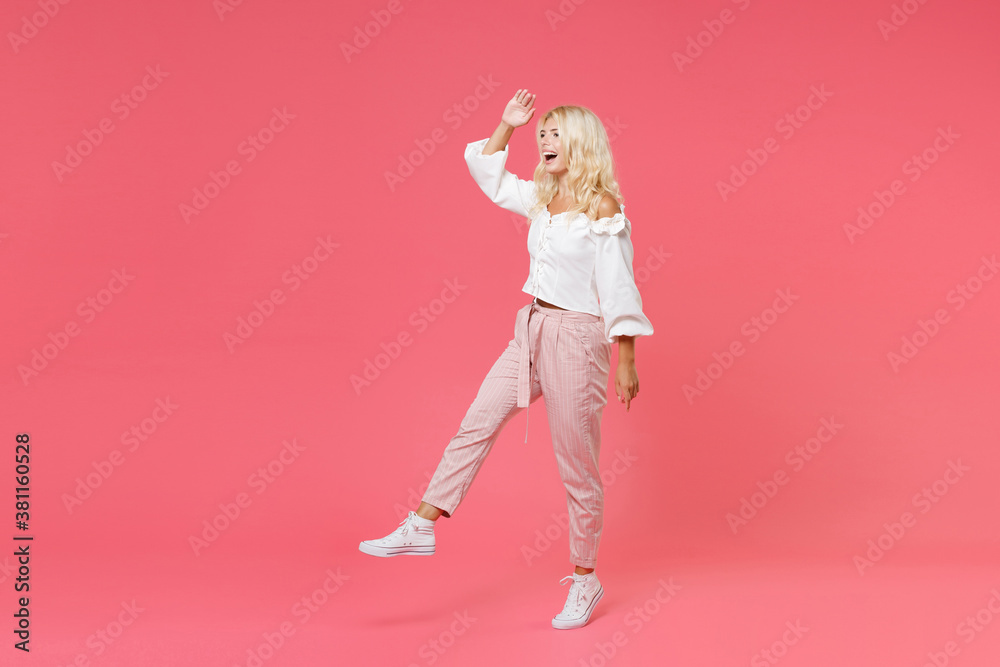 Full length side view portrait of excited young blonde woman 20s wearing white casual clothes holding hand at forehead looking far away distance isolated on bright pink colour background in studio.