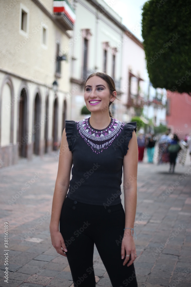 Portraits of a charming red-haired girl with a cute face. Girl posing for the camera in the city center. She has a wonderful mood and a lovely smile, mexican lifestyle, mexican concept queretaro