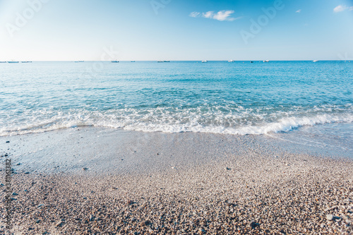 Fototapeta Naklejka Na Ścianę i Meble -  Pebble beach in Condofuri Calabria Italy with fishing boats on the horizon