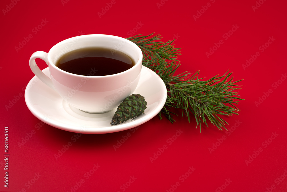 A Cup of coffee on a white saucer, pine branches and cones on a red background. The concept of the new year 2021 and Christmas. A Cup of coffee on a white saucer, pine branches and cones on a red background. The concept of the new year 2021 and Christmas.