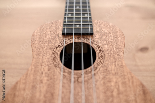 Brown ukulele on wooden background with shallow depht of field