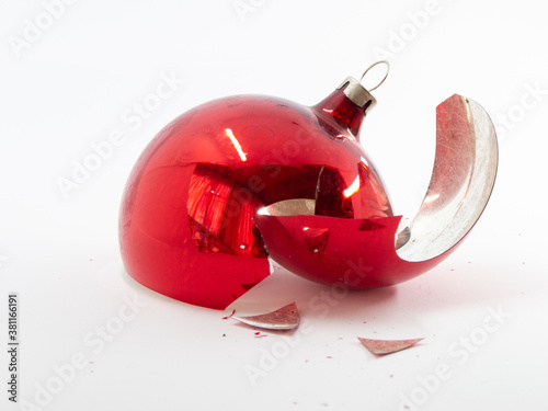 Broken red Christmas bauble in front of white background