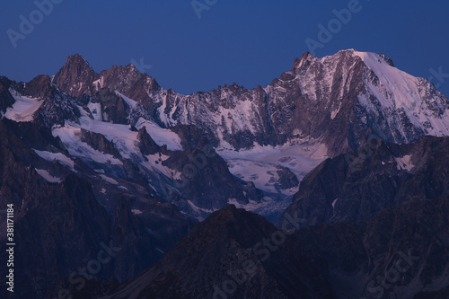 View on purple ridge of Mont Blanc massif with gentle snow and dark rocks during blue hour in clear dark blue sky