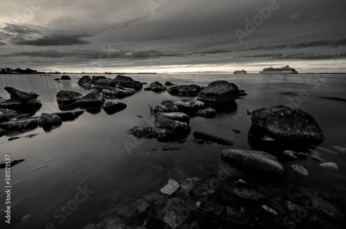 Finnish gulf at sunset with stones and 2 passenger ships in black and white