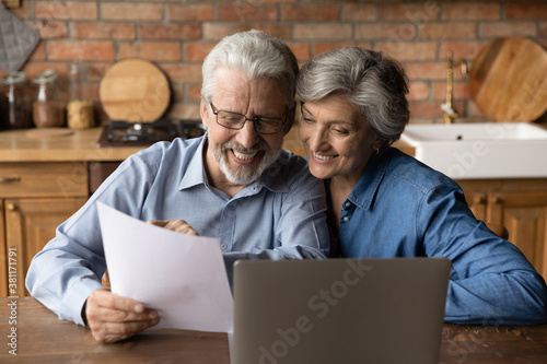 Happy elderly couple read postal paper document satisfied with banking health insurance contract or notice. Smiling mature man and woman consider good news in post paperwork letter correspondence. © fizkes