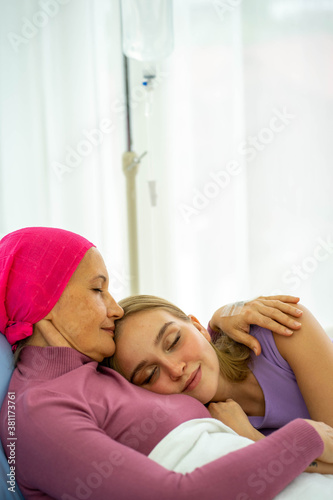 Caucasian senior woman with breast cancer patient lying on hospital bed with young european daughter supporting