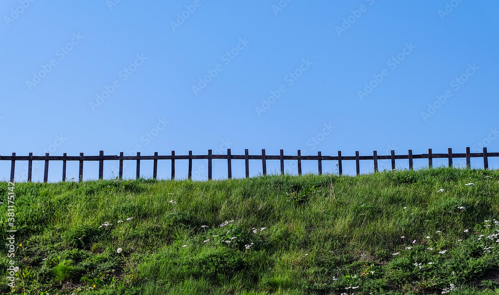 A low wooden fence standing on the lawn against the blue sky