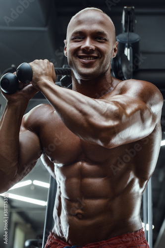 Bodybuilder strong man pumping up abs muscles