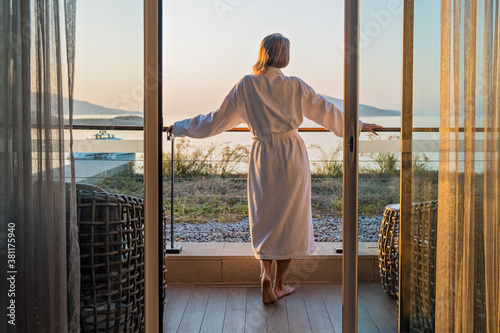 Beautiful woman from back in bathrobe on terrace of hotel room with Sea View