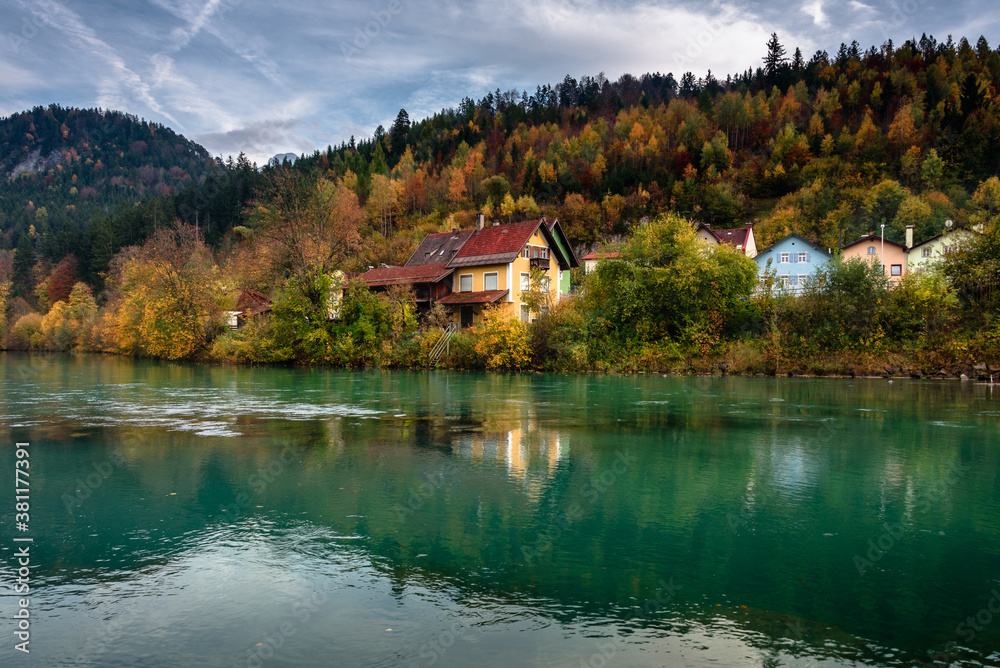 Wonderful landscape of mountain village in fall. View of forest with yellowed foliage, which reflects in water. Fussen. Lech river. Bavaria. Germany.