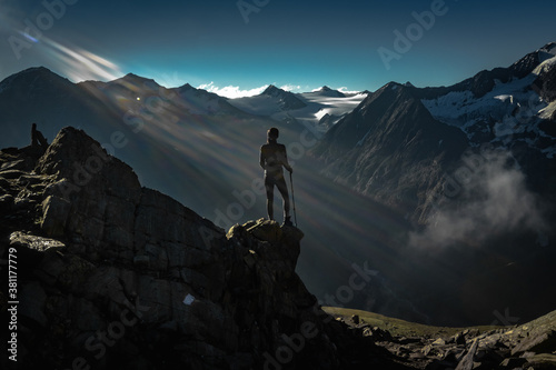 Canvas Print woman looking on the first sunrise light beams from sun in the alps Austria