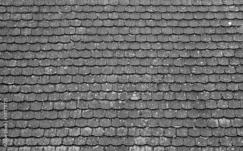 Tiled roof in Europe, Germany. Travel picturesque background and texture photo. Detailed view of roof shingles with moss. Black and white photo