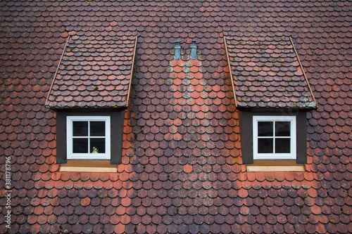 Tiled roof with two windows in Europe, Germany. Travel picturesque background and texture photo. Detailed view of red rare roof shingles. Colorful photo