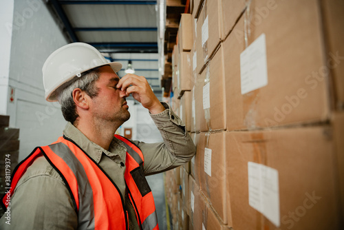 Stressed caucasian male contemplating his failures while leaving against big packaged parcel in factory  photo