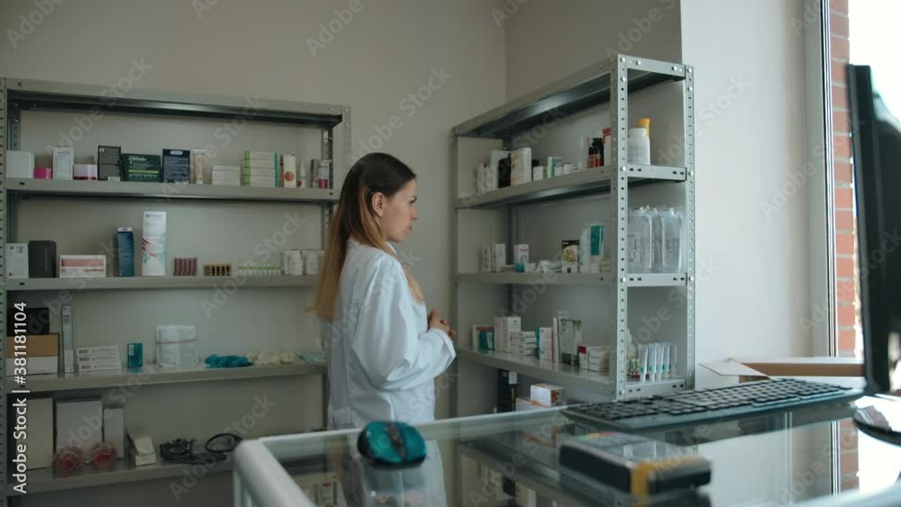 Portrait of a beautiful confident caucasian pharmacist female. Monitoring and checking the availability of medicines on the shelves and a friendly look with a smile at the camera. Drug store interior. Portrait of a beautiful confident caucasian pharmacist female. Monitoring and checking the availability of medicines on the shelves and a friendly look with a smile at the camera. Drug store interior.