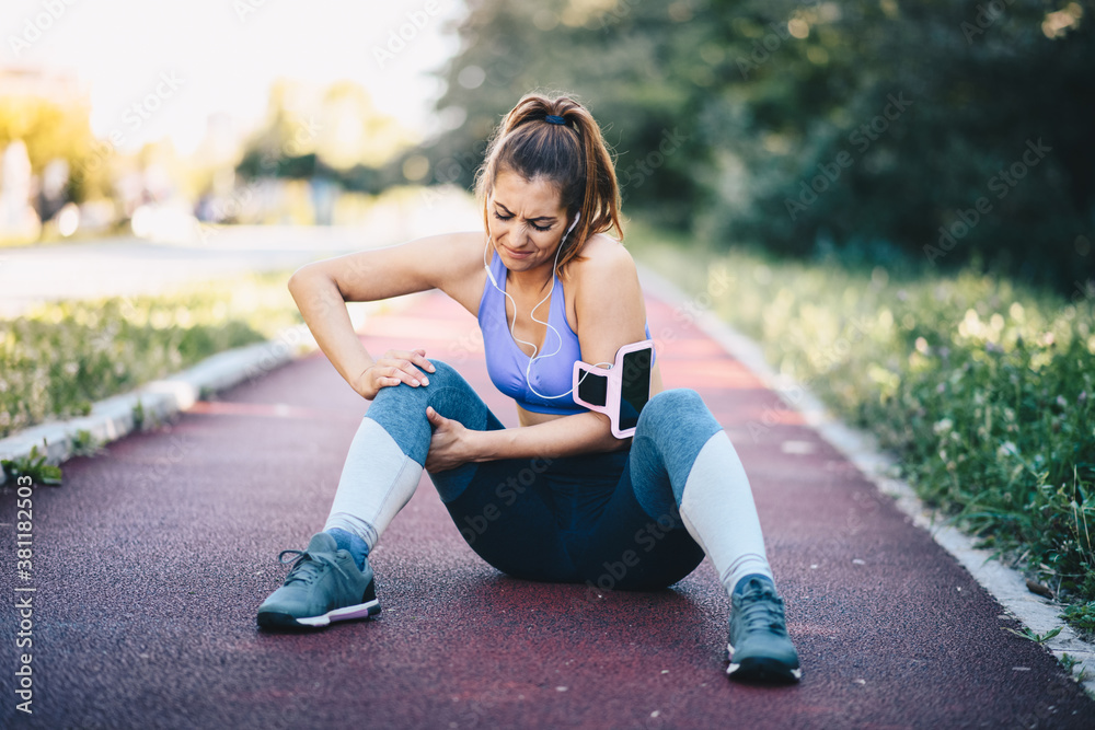 Fototapeta premium A young woman is sitting on a treadmill, has an injury to her right leg, need to rest