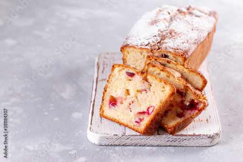 Tableau sur toile Sponge cake with plums and apples with powdered sugar on a light wooden board on a light background