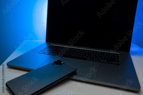 laptop tablet and phone in neon light on the table