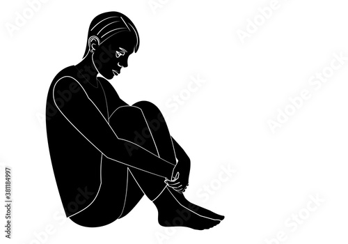 Silueta de joven deprimido sentado en el suelo agarrándose las piernas