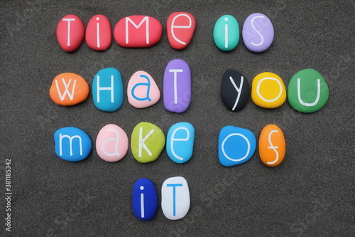 Time is what you make of it, wise words composed with multicolored stone letters over black sand