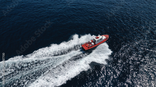 Aerial drone photo of red pilot boat cruising in high speed in Mediterranean deep blue sea offering navigational aid to ships