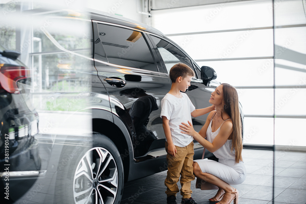 © Andrii - A happy mother with her young son chooses a new car at a car dealership. Buying a car © Andrii - A happy mother with her young son chooses a new car at a car dealership. Buying a car