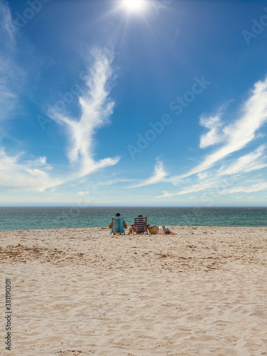 Couple on a lonely beach looking at the sea on a beautiful summer day. Peace, spirituality and the concept of consciousness.