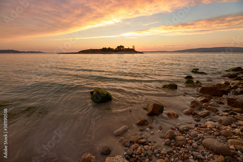 Reddish sunset on round stone beach on the beach called Santo do Mar, in Galicia.