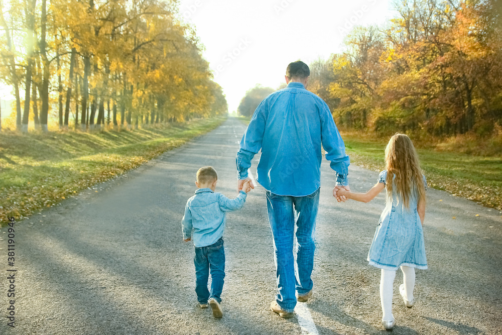 A Happy parent with child are walking along the road in the park on nature travel A Happy parent with child are walking along the road in the park on nature travel