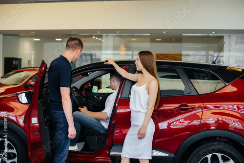 A happy young couple chooses and buys a new car at a car dealership. Buying a new car © Andrii