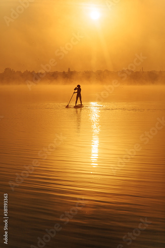 Muscular man on distance paddling on sup board