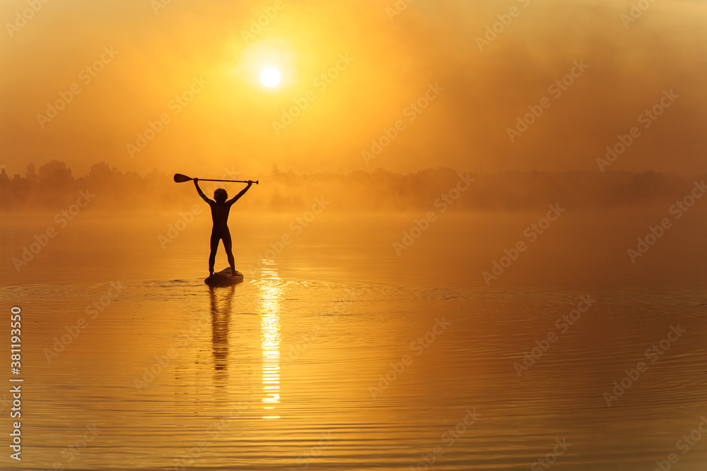 Strong man standing on sup board with paddle above head