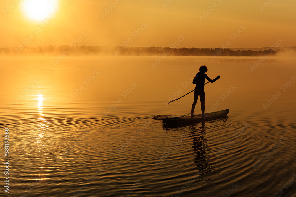 Active man using paddle for swimming on sup board