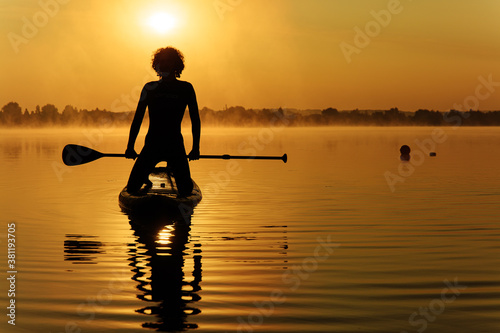 Sportyguy in silhouette swimming on sup board with paddle © Tymoshchuk