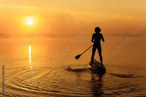 Silhouette of man floating on sup board on foggy lake © Tymoshchuk