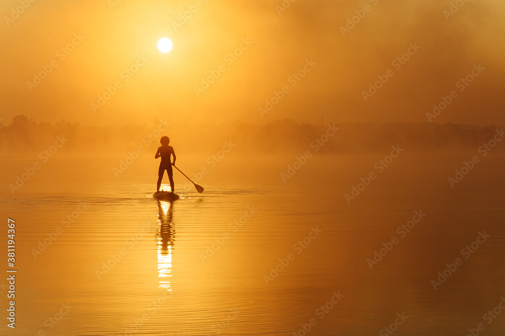 Young man practising in sup boarding during morning time