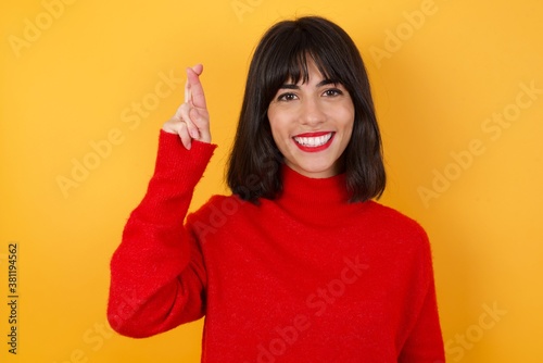 фотографія Caucasian brunette woman wearing red casual sweater isolated over yellow backgro